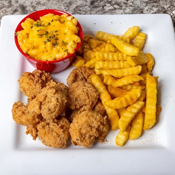 A plate of fried chicken nuggets, crinkle-cut fries, and a red bowl of macaroni and cheese.